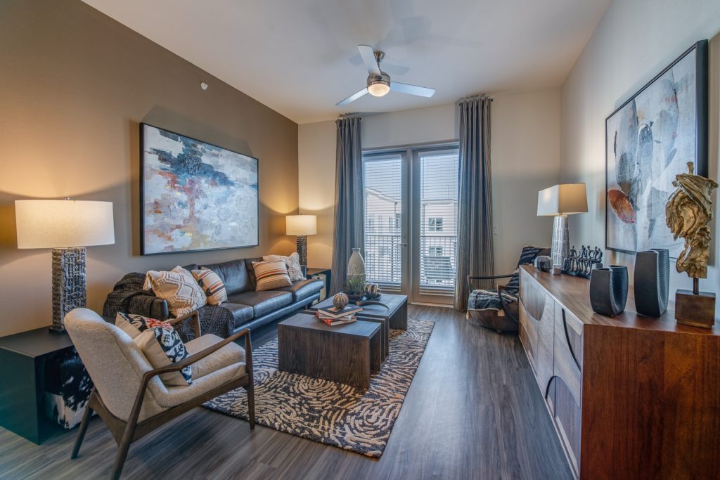 living room with wood flooring, patio access, ceiling fan, decor and accent wall