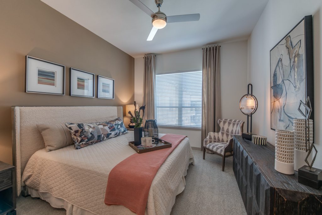 bedroom with decor, carpet, ceiling fan, window, and accent wall