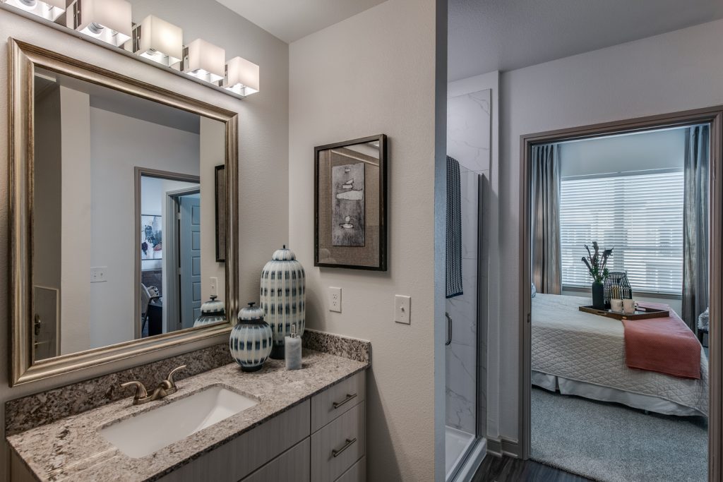 bathroom with standup shower, single mirror and sink, granite countertops, and decor