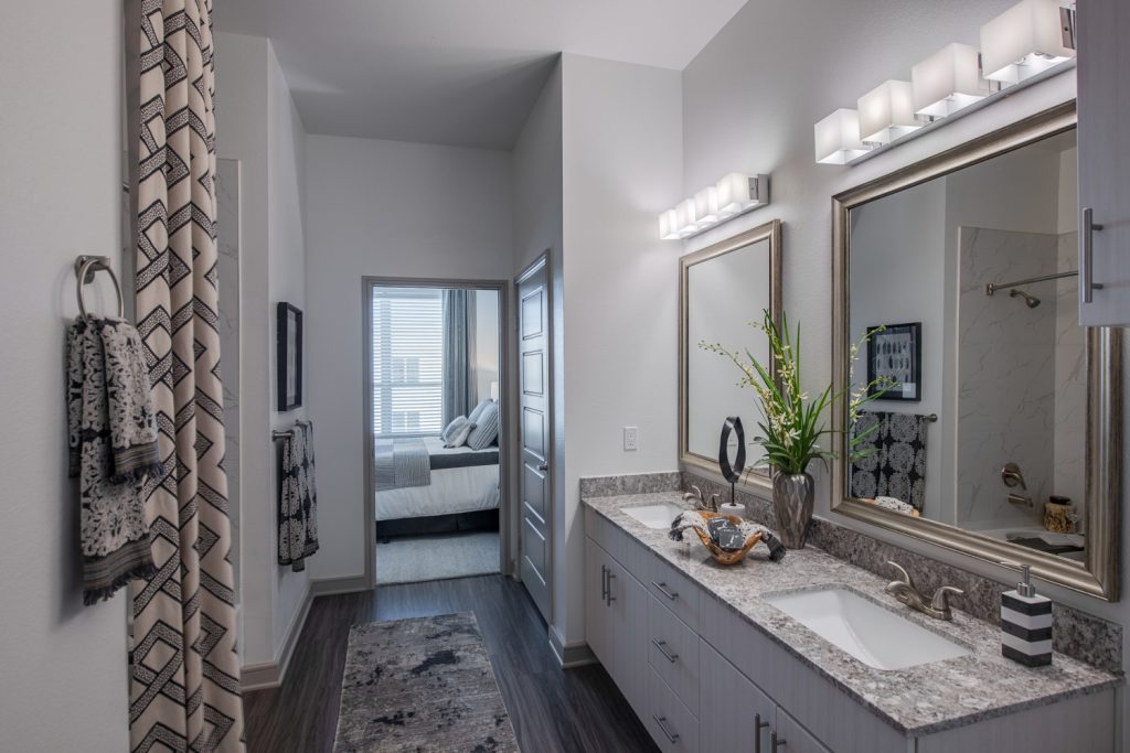 bathroom with dual sink and mirrors, decor, and wood flooring