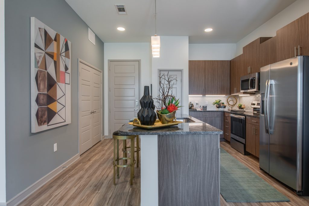 kitchen area with island, single sink, steel appliances, and wood cabinets