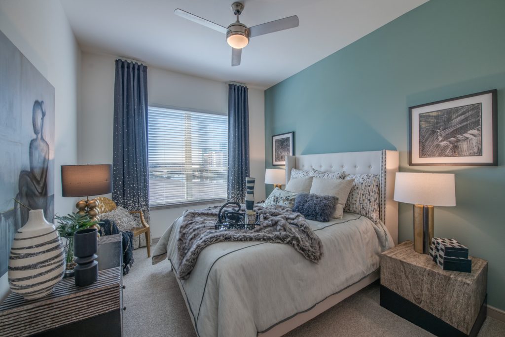 bedroom with window, ceiling fan, accent wall, carpet, and decor