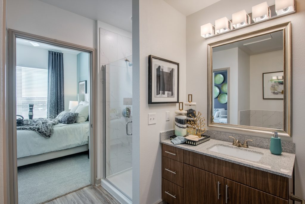 bathroom with single sink, large mirror, granite countertops, and standup shower