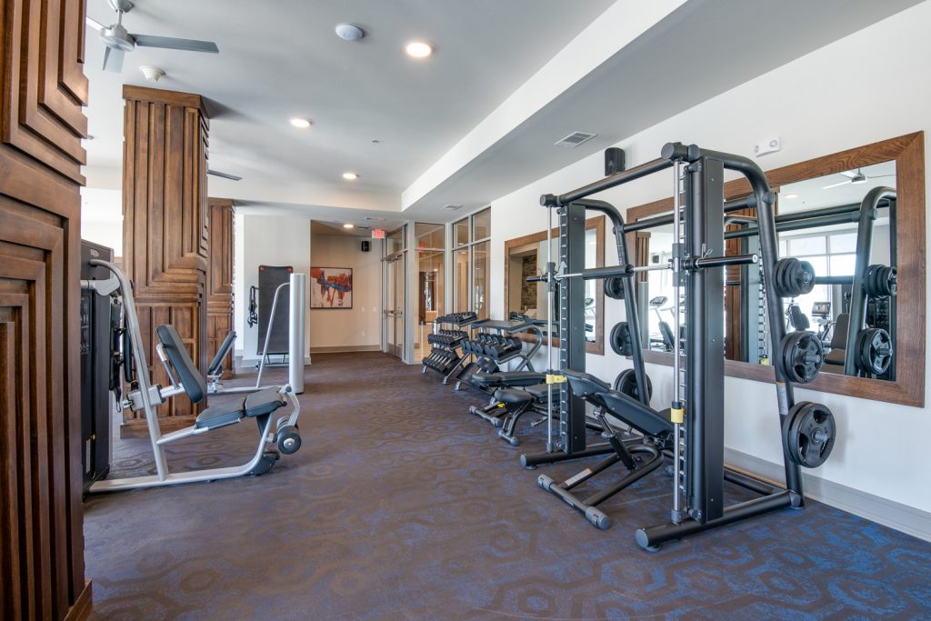 fitness center with weight machines, large mirrors, and ceiling fans