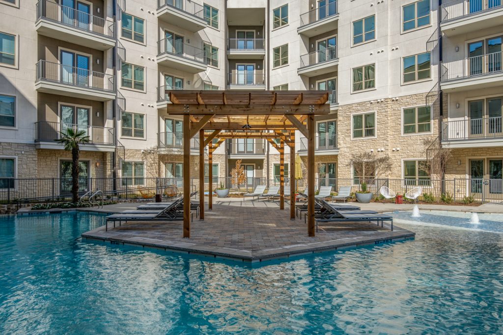 pool with lounge chairs, wood pergola, and palm trees