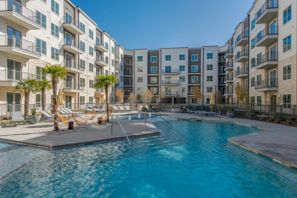 pool with lounge chairs, seating, and palm trees