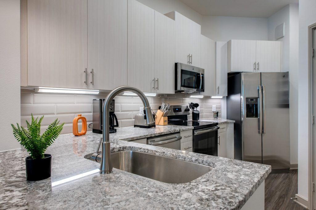 kitchen with granite countertops, large sink, steel appliances, and wood flooring