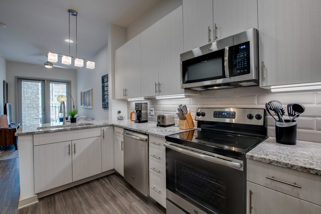 kitchen with granite countertops, overhead lighting, large sink, and steel appliances