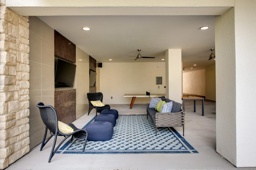 the cave area with tvs, seating, and ping pong table and ceiling fan